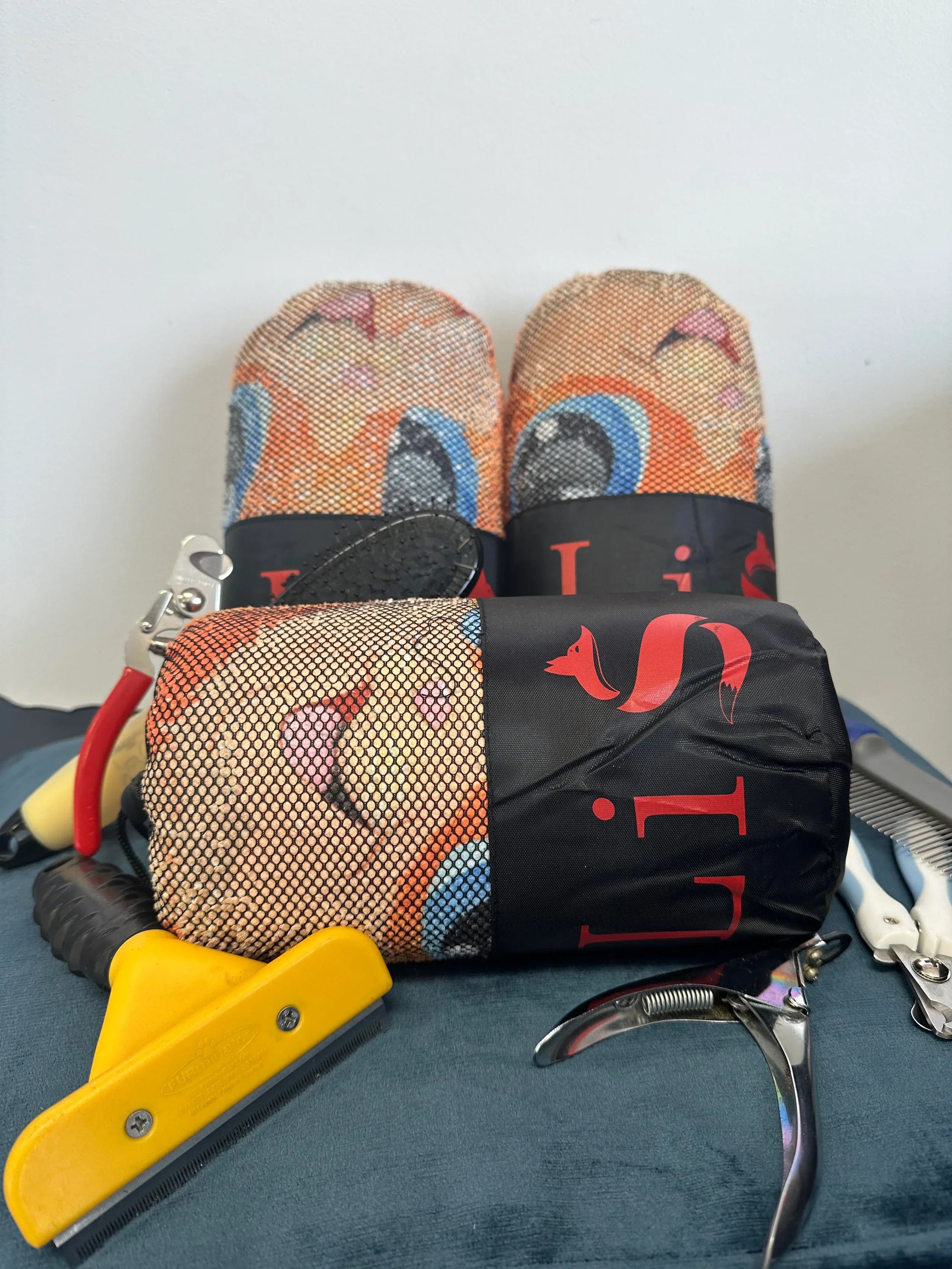 Pair of colorful slippers with a black strap, a yellow tool, and a metal object on a blue surface.