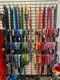 Colorful dog collars and leashes hanging on a display rack.